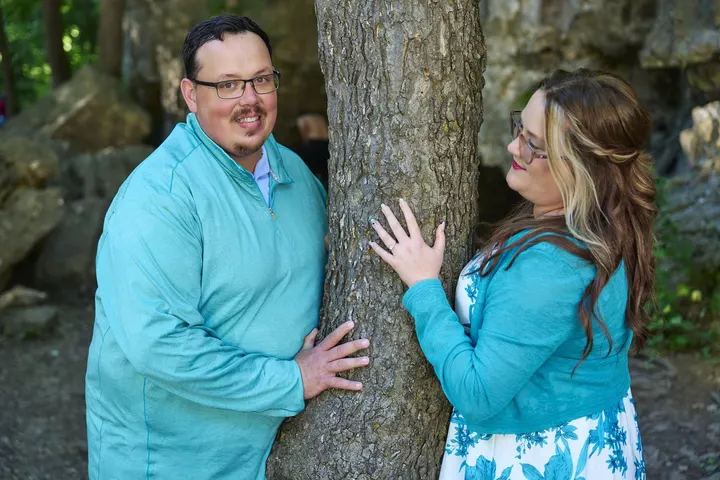 Kimberly and Stephen playfully peeking around a tree